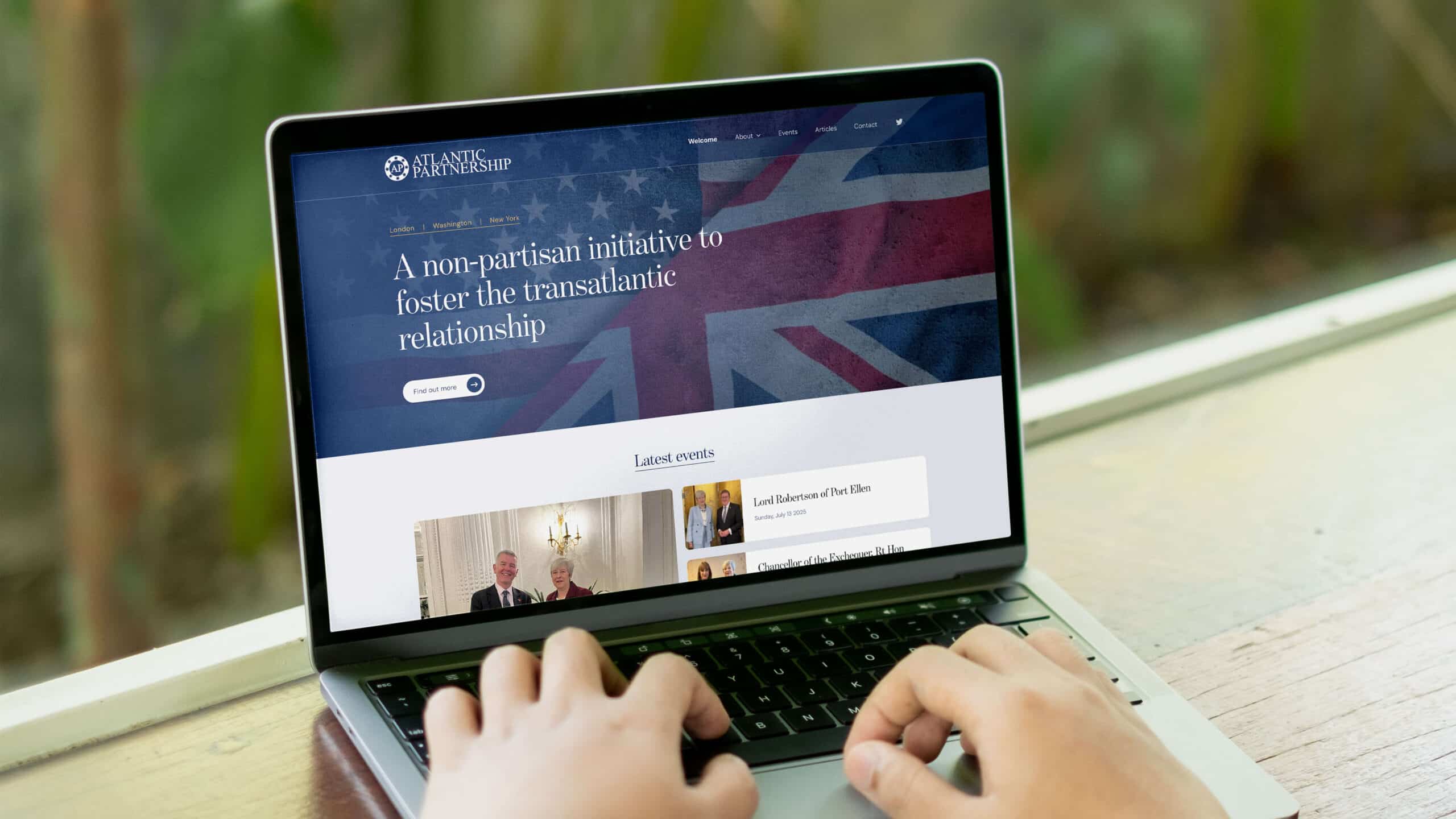 The redesigned Atlantic Partnership homepage on a laptop, with the headline 'A non-partisan initiative to foster the transatlantic relationship' over US and UK flag imagery